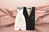 Esküvői meghívó - 115x230 mm - a vőlegényruha alakú tasak fekete matt kartonból készült, fényes ezüst díszítéssel - 2 db betétlap tartozik hozzá: az egyik a vőlegény inge, a másik pedig egy menyasszonyi ruha, mindkettő ezüst gyöngyházfényű papír fekete, illetve fényes ezüst díszítéssel - a lap hátsó fekete részére kis kártya helyezhető a pár vagy a meghívott nevével